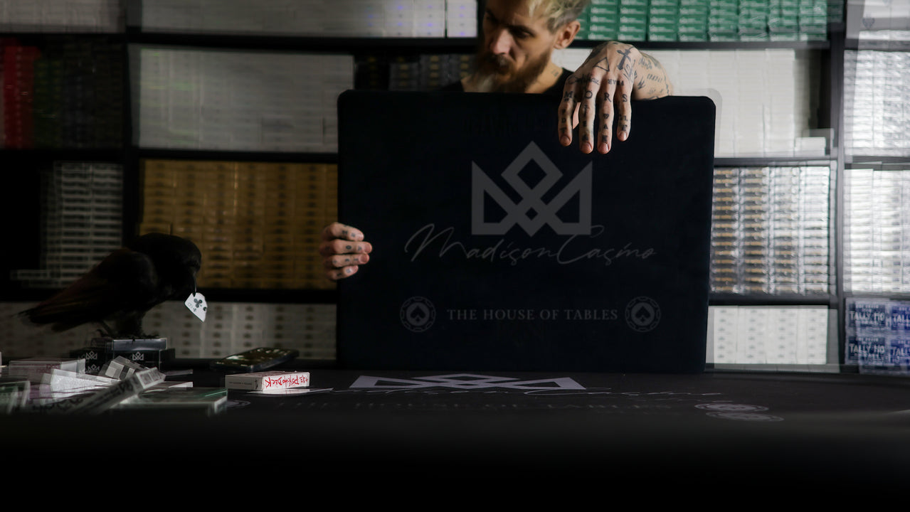 Person holding a black laptop with 'The House of Tables' logo in a dimly lit room.