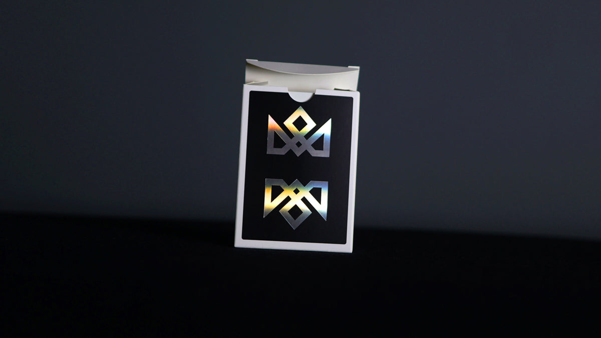 Holographic acolyte magic playing cards by Daniel Madison. Image shows rainbow effect on tuck box. Black background and holo acoloyte inverted logos.