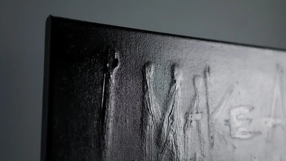 Detail of SURVIVAL painting by Daniel Madison showing raised texture where original message remains visible beneath black paint, representing honesty hidden behind insecurity